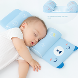Baby sleeping on a blue pillow with cartoon face design on a white background